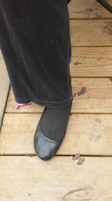 Pieds de femme en collants noirs avec pantalons et chaussures plates