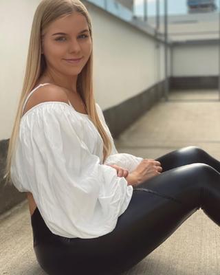 Blondes Mädchen in glänzenden Lederleggings